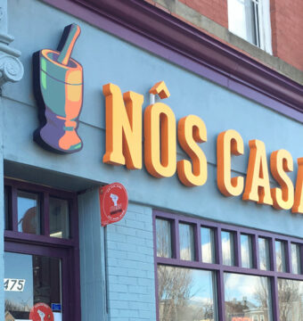 Blue facade with orange and yellow "Nos Casa" sign