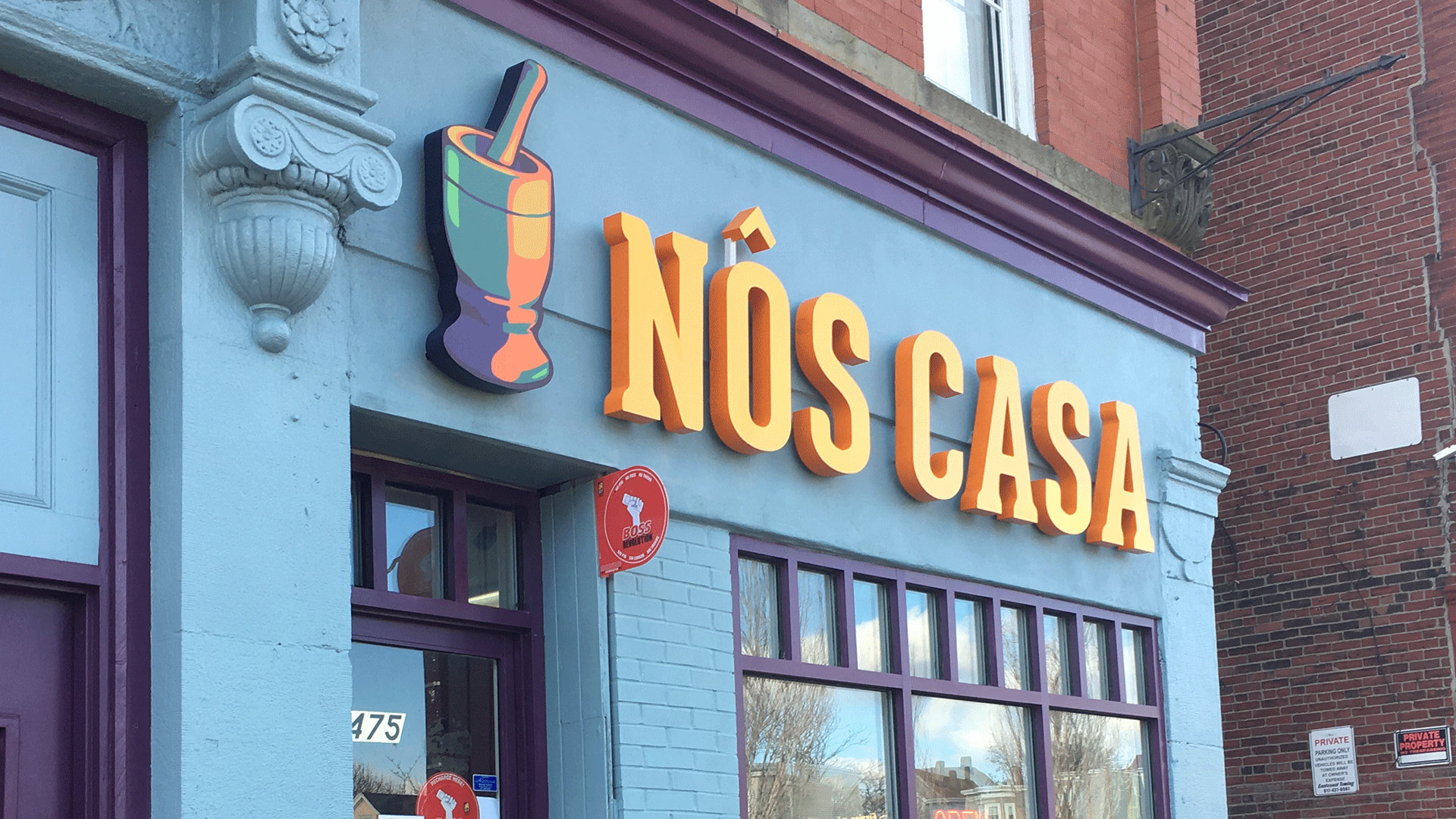 Blue facade with orange and yellow "Nos Casa" sign